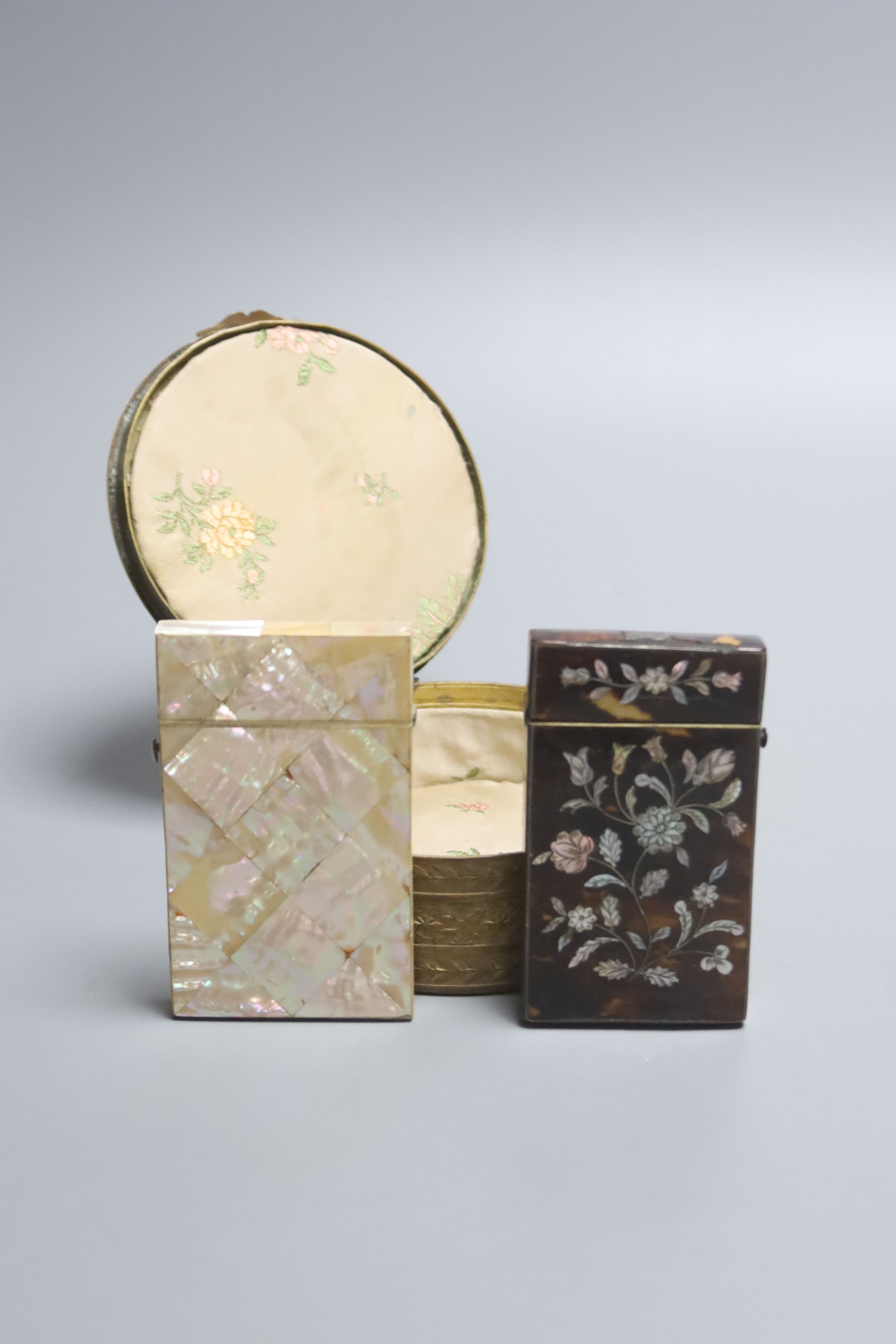 A Victorian tortoiseshell and mother of pearl card case, similar mother of pearl case and a porcelain mounted brass casket with enamel